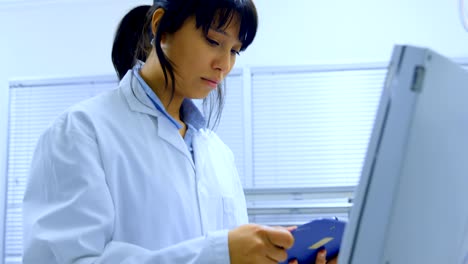 Female-scientist-looking-at-clipboard-4k