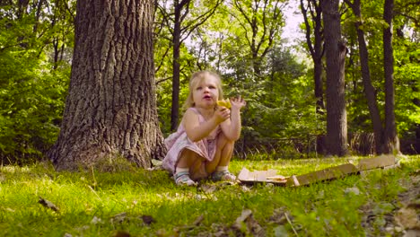 Kleines-Mädchen-im-Park-sitzen-und-Essen-pizza