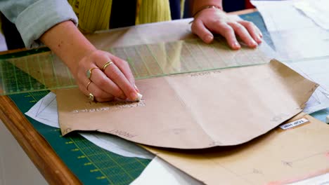 Fashion-designer-marking-on-brown-paper-at-desk-4k