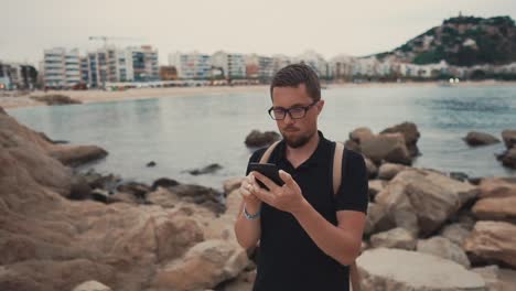 Hombre-mirando-su-teléfono-en-una-orilla.