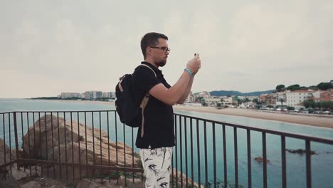 Male-tourist-shooting-beach-on-smartphone.