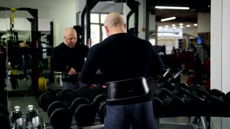 Bodybuilder-takes-heavy-dumbbells,-looks-at-himself-in-the-mirror,-does-the-exercise-4K-Slow-Mo