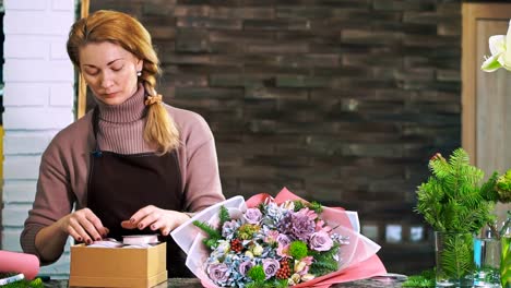 Una-floristería-mujer-elija-una-cinta-para-adornar-un-ramo-de-flores.