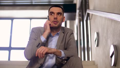 businessman-calling-on-smartphone-at-office-stairs