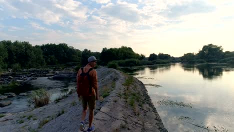 Hombre-joven-caminando-por-la-orilla-del-río