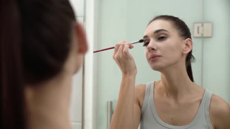 Makeup.-Woman-Applying-Eyeshadows-And-Looking-At-Mirror