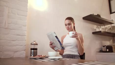 Mujer-con-periódico-de-beber-café-en-el-desayuno-en-la-cocina