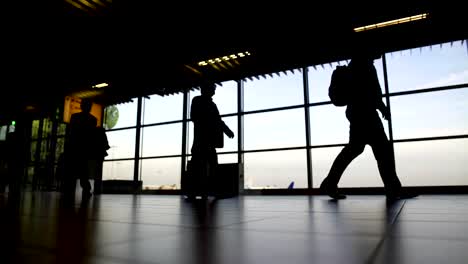 Silhouetten-von-Menschen-mit-Koffern-Umzug-in-Abflughalle-am-Flughafen