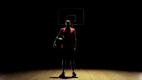 A-basketball-player-looks-at-camera,-throws-ball-and-exits.