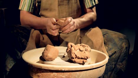 Potters-hands-work-on-several-large-lumps-of-crude-clay.