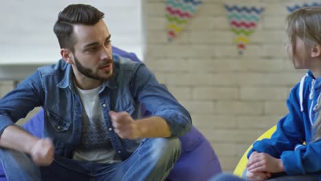 Young-Male-Teacher-Talking-with-Little-Girls-in-Kindergarten