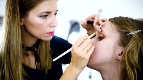 Mujer-joven-aplicar-maquillaje-para-modelo-en-el-salón