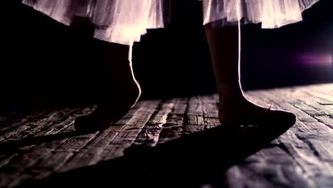 close-up,-in-rays-of-spotlight,-on-the-stage-of-the-old-theater-hall.-ballerina-in-white-ballet-skirt,-raises-on-toes-in-pointe-shoes,-performs-elegantly-a-certain-ballet-exercise,-pointe