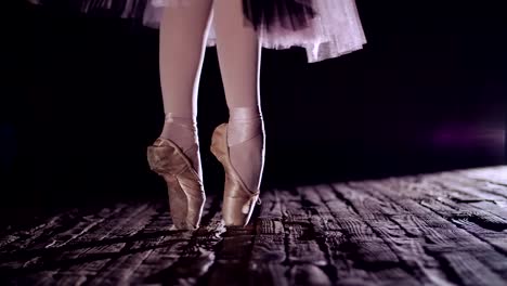 close-up,-in-rays-of-spotlight,-on-stage-of-old-theater-hall.-ballerina-in-white-ballet-skirt,-raises-on-toes-in-pointe-shoes,-performs-elegantly-a-certain-ballet-exercise,-en-tournaht-suivi