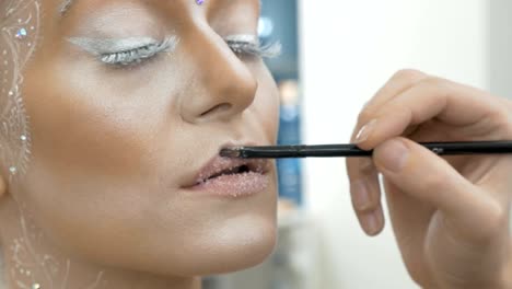 Der-Make-up-Künstler-malt-das-Modell-Lippen-mit-einer-speziellen-Bürste.-Close-up