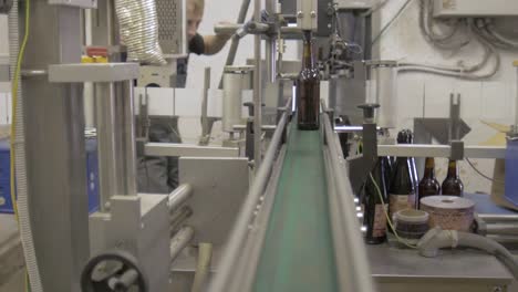 Man-working-on-a-factory.-Bottles-on-conveyor-line.