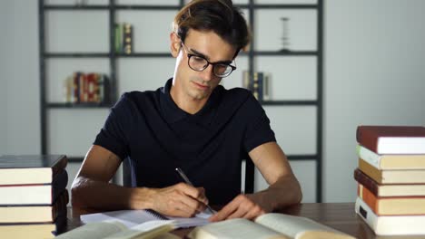 Inteligente-estudiante-sentado-en-la-mesa-y-escribiendo-en-el-cuaderno.-Preparación-antes-del-examen,-aprendizaje-en-casa.