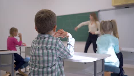 Kinder-unterrichten,-Schulkind-bei-Lektion-anhören-Erzieher-an-der-Tafel-in-fokussierten-im-Klassenzimmer-der-Schule