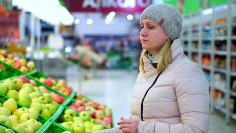 Mujer-en-ropa-de-invierno-recoge-fruta-en-un-supermercado.-Mira-las-manzanas.