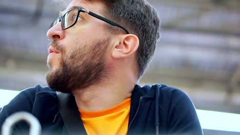 A-man-with-a-beard-in-glasses-walks-through-a-supermarket.-He-is-waiting-near-the-grocery-cart.