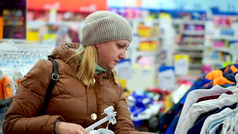 A-woman-in-winter-clothes-came-to-the-children's-clothing-store.-She-chooses-her-child