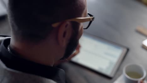 Man-using-tablet-at-table-near-cup