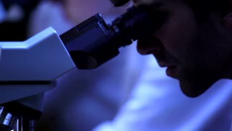 Close-up-of-a-researcher-looking-into-a-microscope-in-the-lab