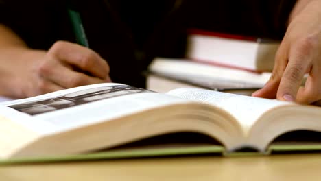 Close-up-of-a-student-looking-through-a-text-book