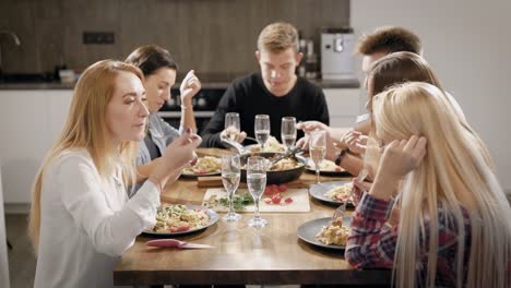 Gente-joven-alegre-comedor-en-mesa-de-cocina