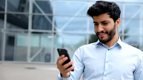 Handsome-Man-Using-Phone-Near-Business-Center-On-Street