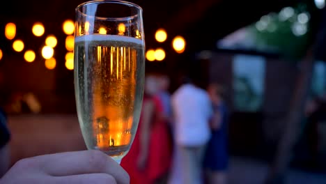 Männliche-Hand-hält-ein-Glas-Champagner-auf-einer-party