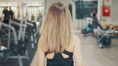 Slowmotion-shot-of-Young-fit-woman-walking-through-gym.