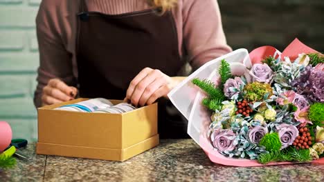 A-woman-florist-choose-a-ribbon-for-decorating-a-bouquet.-Hands-close-up.