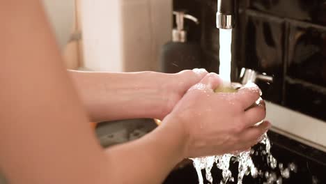 Washing-Fruits-With-Clean-Water-In-Kitchen-Closeup