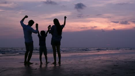 SLOW-MOTION,-familia-asiática-silueteado-mirando-al-atardecer-con-feliz-emoción-en-la-playa-juntos.-Concepto-de-familia,-vacaciones-y-viajes.