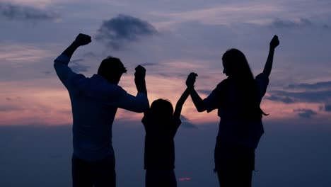 SLOW-MOTION,-Silhouetted-Asian-family-looking-to-sunset-with-happy-emotion-at-Beach-together.-Family,-Holiday-and-Travel-concept.