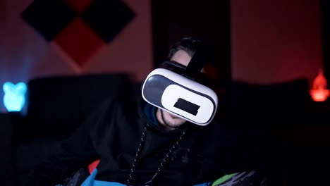 Hombre-sentado-en-el-sofá-en-casa-jugando-juegos-y-viendo-películas-con-gafas-de-realidad-virtual