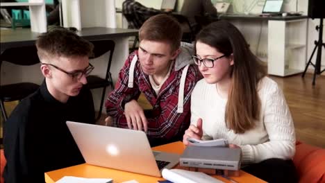 Students-looking-at-laptop-screen-and-discussing-something-in-classroom