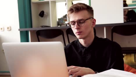 Junger-Mann-Student-in-Gläsern-mit-Laptop-im-Klassenzimmer