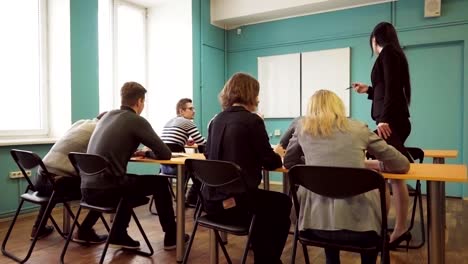 Woman-teacher-check-students-progress-during-a-lesson-in-classroom