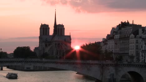 Ein-Boot-vorbei-an-Notre-Dame-den-Sonnenuntergang-im-Hintergrund