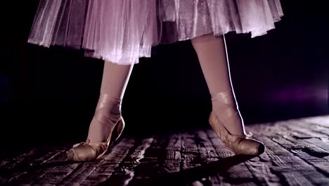 close-up,-in-rays-of-spotlight,-on-the-stage-of-the-old-theater-hall.-ballerina-in-white-ballet-skirt,-raises-on-toes-in-pointe-shoes,-performs-elegantly-a-certain-ballet-exercise,-relleve