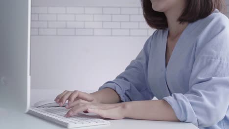 Hermosa-joven-sonriente-mujer-asiática-trabajando-en-ordenador-portátil-mientras-está-sentado-en-una-sala-de-estar-en-casa.-Mujer-de-negocios-asiáticos-trabajando-en-su-oficina-en-casa.-Disfrutando-en-casa.