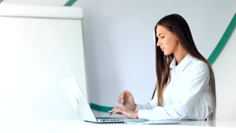 Beautiful-businesswoman-working-with-laptop-in-white-office