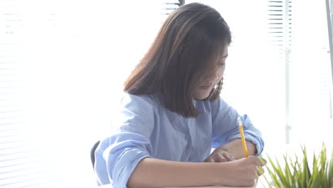 Beautiful-young-smiling-asian-woman-working-on-laptop-while-sitting-in-a-living-room-at-home.-Asian-business-woman-working-in-her-home-office.-Enjoying-time-at-home.