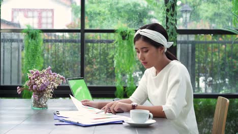 Hermosa-joven-sonriente-mujer-asiática-trabajando-en-ordenador-portátil-mientras-está-sentado-en-la-sala-de-estar-en-casa.-Mujer-de-negocios-asiática-de-trabajo-finanzas-documentos-y-calculadora-en-su-oficina-en-casa.-Disfrutando-en-casa.