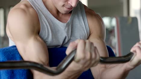 A-shirtless-guy-at-the-gym,-trains-his-body-to-stay-fit-and-have-defined-muscles.-The-athlete-raises-heavy-weights-and-fatigue.