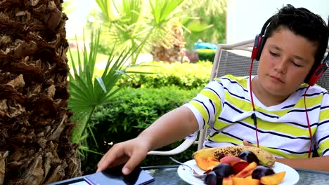 Child-with-headphone-using-smartphone-at-the-garden