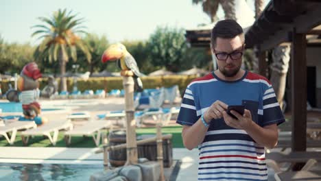 Businessman-is-reading-e-mail-in-smartphone,-during-vacation-in-hotel,-walking