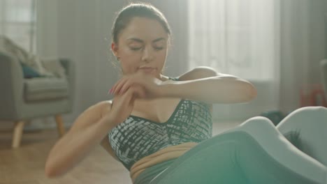 Slow-Motion-Close-Up-Shot-of-a-Beautiful-Confident-Busty-Fitness-Female-in-an-Athletic-Top-is-Doing-Abdominal-Workout-in-Her-Bright-and-Spacious-Apartment-with-Minimalistic-Interior.